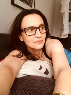 Woman wearing glasses lying on a couch.
