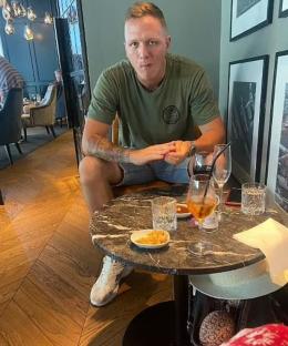 Man sitting at a table with drinks and snacks.
