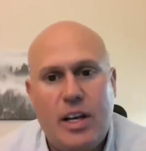 Close-up of a bald man speaking.