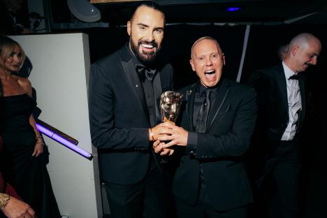 Rylan Clark and Robert Rinder holding a BAFTA award.