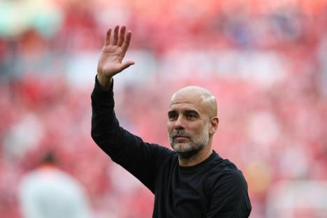 Pep Guardiola waving to fans.