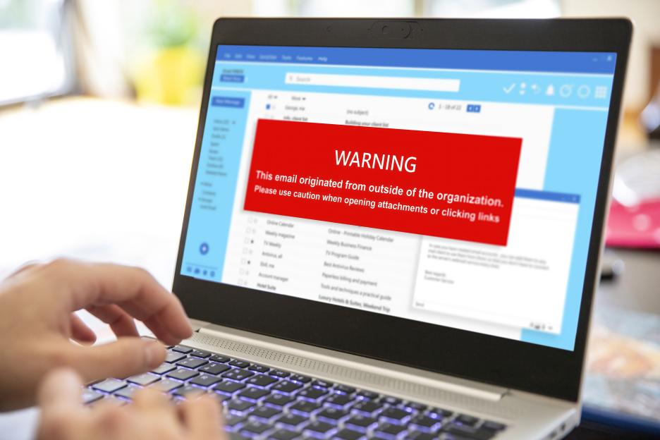 Laptop screen displaying an email with a red warning banner about external origin and attachments.