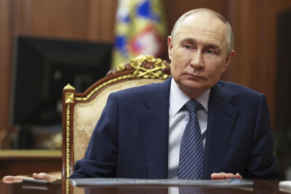 Vladimir Putin sitting at a table.