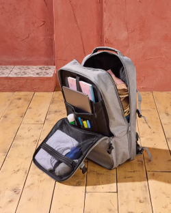 Grey backpack open, showing its contents: laptop, notebooks, clothes, and other items.