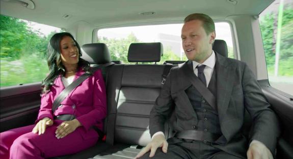 Two people in business attire seated in the back of a car.