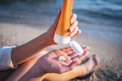 Woman applying sunscreen at the beach.