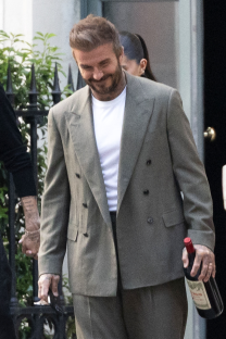 Man in suit carrying a bottle of wine.