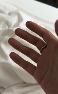 Hand with ring on white bedding.