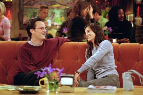 Monica and Chandler from Friends on an orange couch.