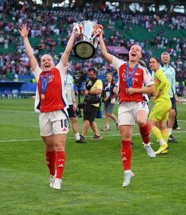 Arsenal's Kim Little and Beth Mead celebrating with the UEFA Women's Champions League trophy.