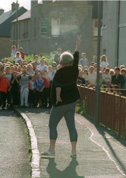 Woman giving peace sign to a crowd of children.