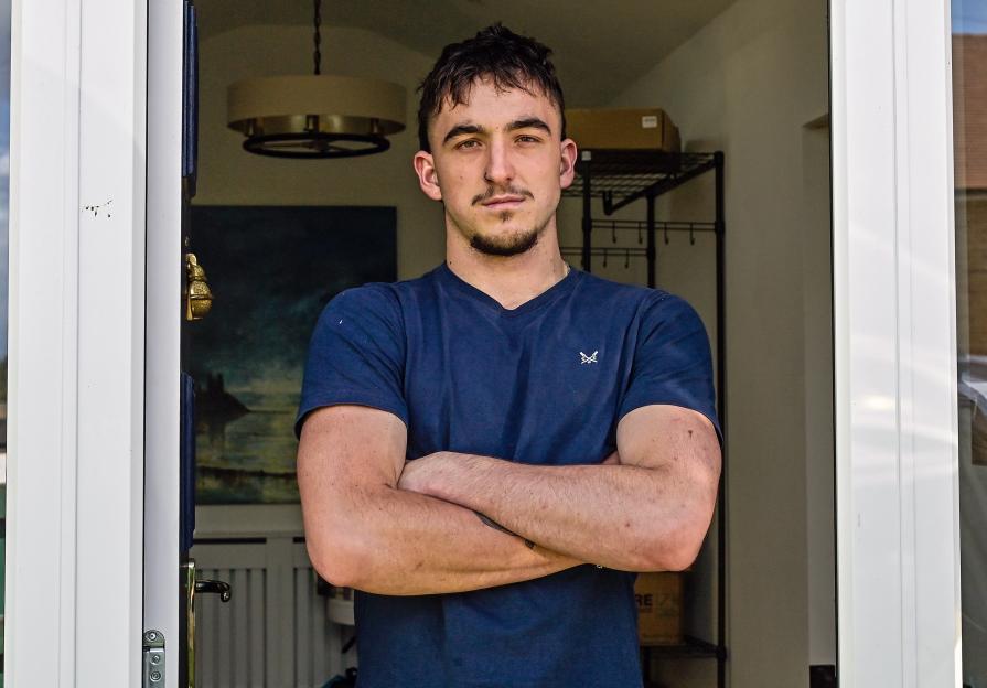 Portrait of a young man with arms crossed, standing in a doorway.