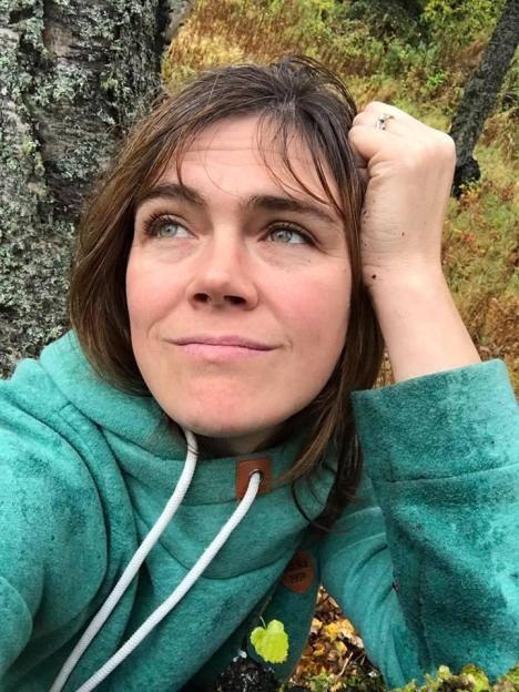 Woman in teal hoodie looking upward.