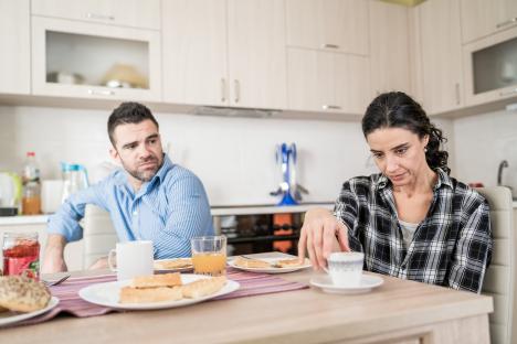 A couple sits at a kitchen table during a tense breakfast.