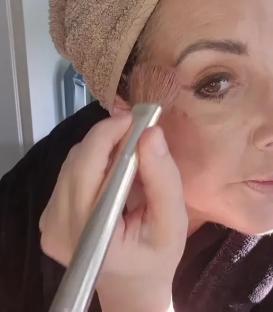 Woman applying makeup to lift her face; part 2.