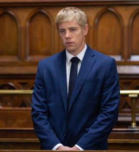 Man in a blue suit in a courtroom.