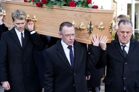 Pallbearers carry a casket at a funeral.