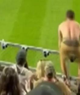 A shirtless man falling from a stadium railing.