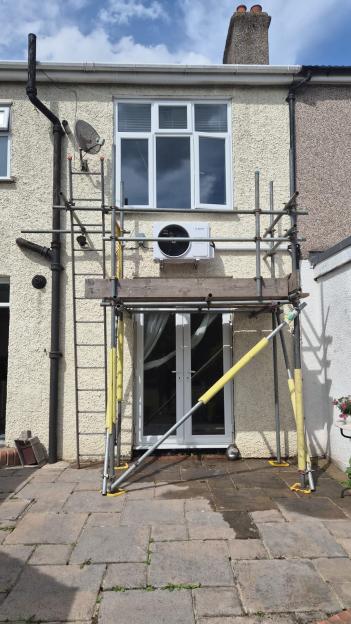 Scaffolding erected against a house with a new air conditioning unit installed.