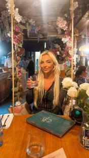Woman sitting on a swing at a restaurant, holding a glass of water.