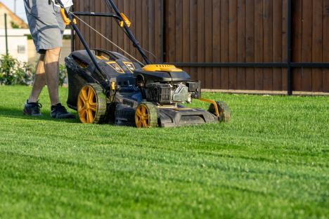 Man mowing lawn with lawnmower.