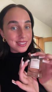 Woman holding up a bottle of perfume that is a dupe of a designer scent.