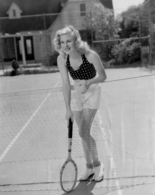 Ginger Rogers at Grand Central Terminal with tennis rackets and luggage.