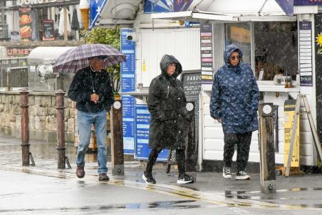 People walking in the rain wearing rain jackets and using umbrellas.