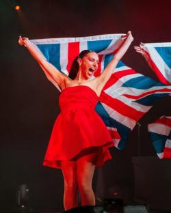 Woman in red dress holding a Union Jack flag.