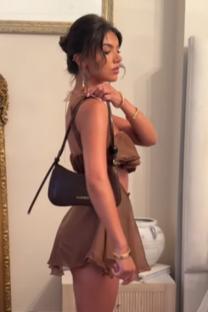 Woman in brown outfit holding a brown purse.