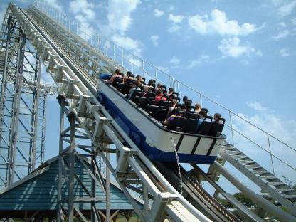 Roller coaster car ascending a hill with passengers.