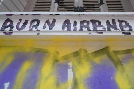 Graffiti reading "Burn Airbnb" on a wall.