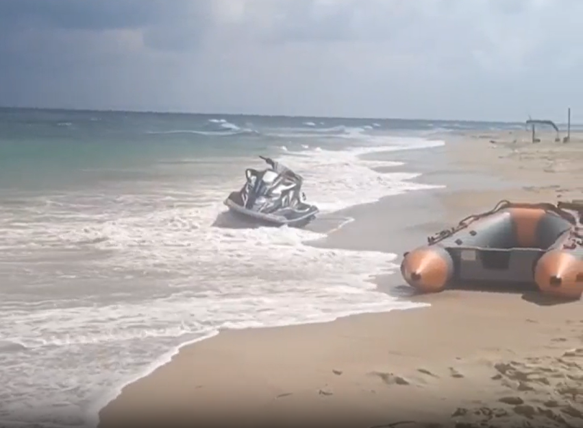 Jet ski and inflatable boat on a beach.