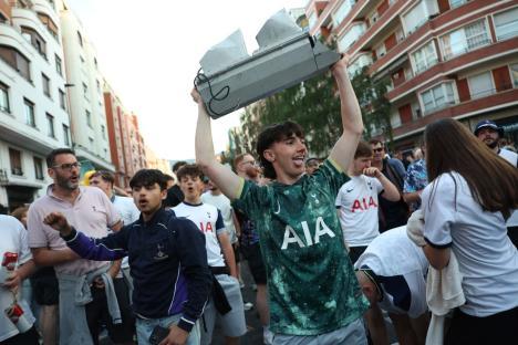 A man holds up a broken traffic light while celebrating with other soccer fans.