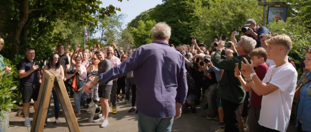 Jeremy Clarkson surrounded by a crowd of people taking photos.