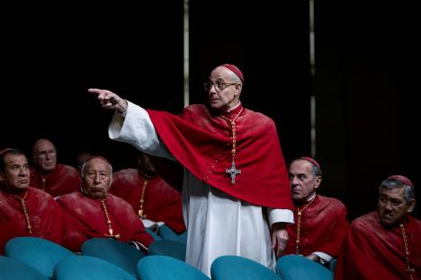 Stanley Tucci as a cardinal pointing in a scene from a film.