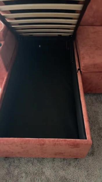 Pink sofa with a bed frame pulled out from underneath, revealing hidden storage.