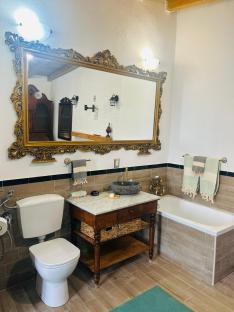 Renovated bathroom with ornate mirror, stone sink, and freestanding tub.