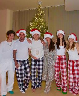 The Beckham family in matching Christmas pajamas in front of a Christmas tree.