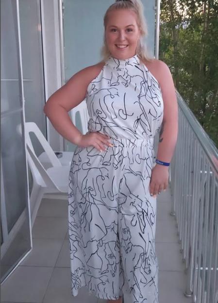 Woman in abstract print jumpsuit on balcony.