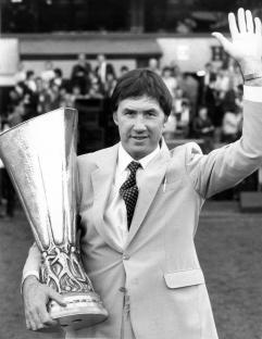 Black and white photo of Keith Burkinshaw holding the UEFA Cup and waving to fans.