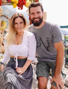 Couple posing in front of fruit and vegetable display in Italy.