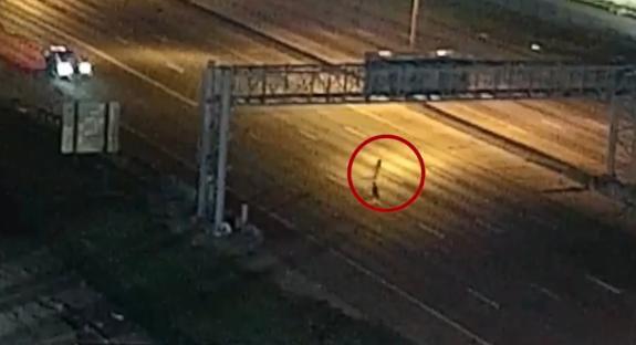 Surveillance image of an escaped prisoner walking on a highway.
