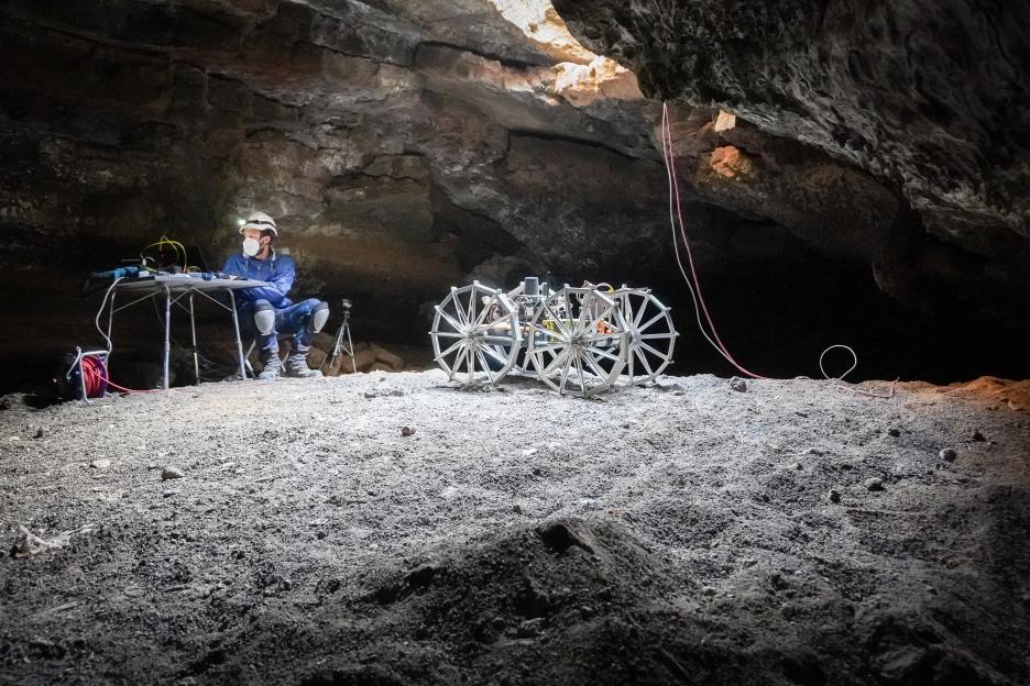 A researcher tests a robot in a lava tube, simulating exploration of lunar or Martian caves.