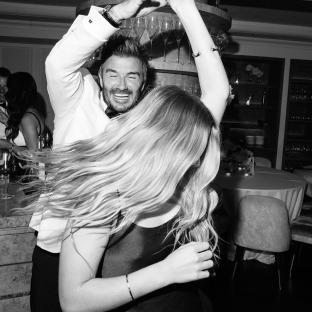 Black and white photo of David Beckham dancing with a woman at his 50th birthday party.