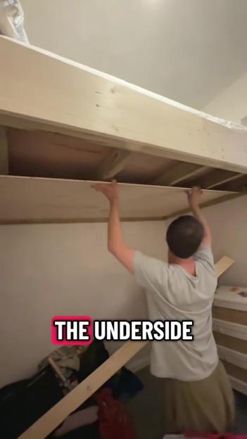 A person installing the underside of a new loft bed.