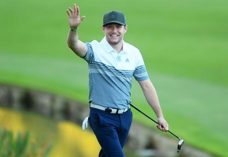 Niall Horan waving to the crowd at a golf tournament.