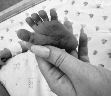 A hand gently holding a newborn's foot.