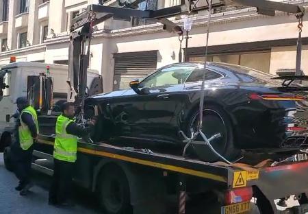 A black Mercedes AMG GT Coupe being towed away on a flatbed tow truck.