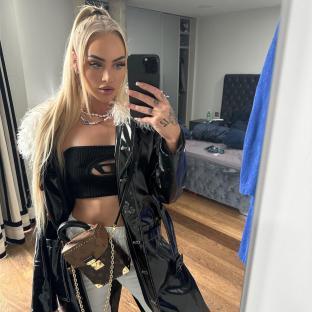 Woman taking a selfie in a black leather coat and black top.